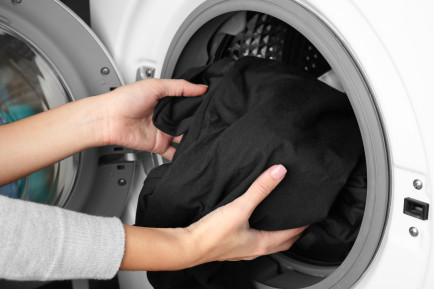 Çamaşır makinesine kıyafet koyarak kişi